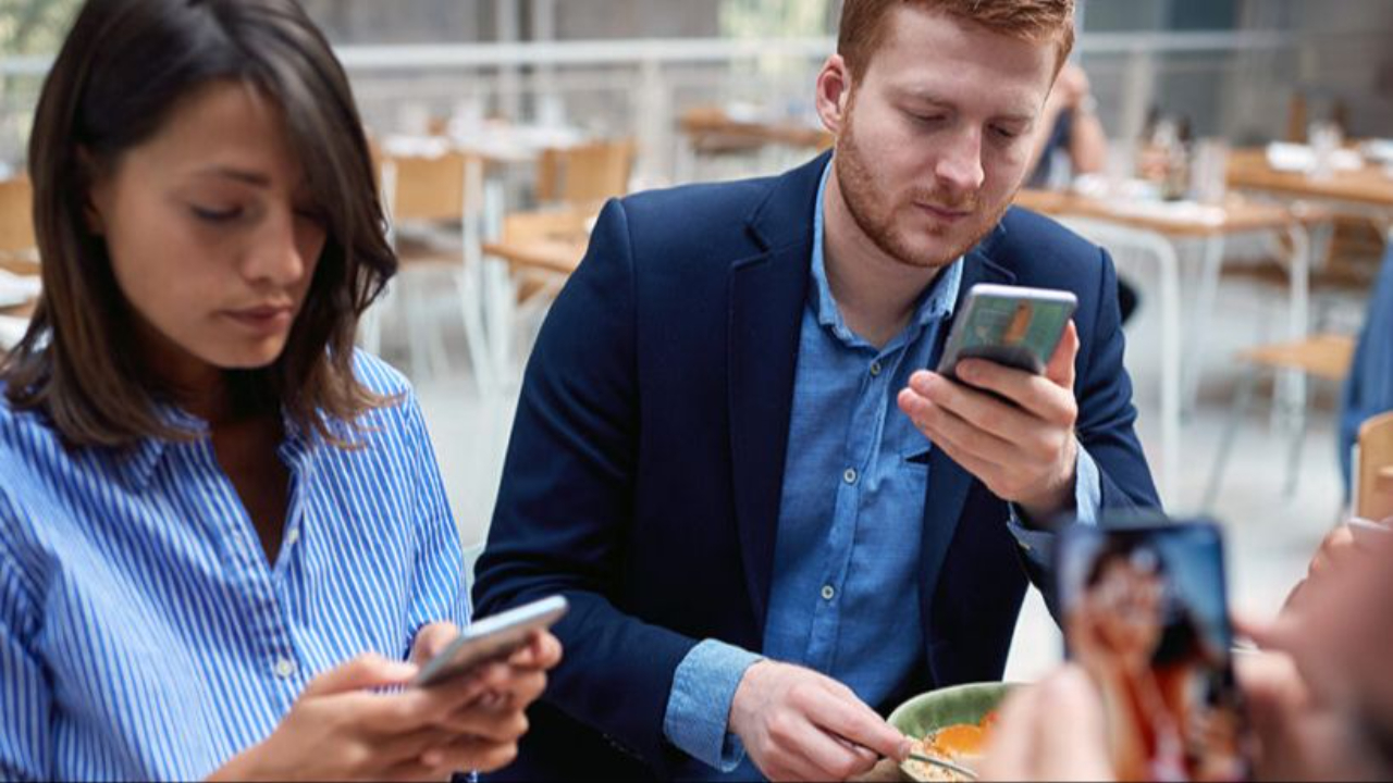 Two people looking at their phones in a public space
