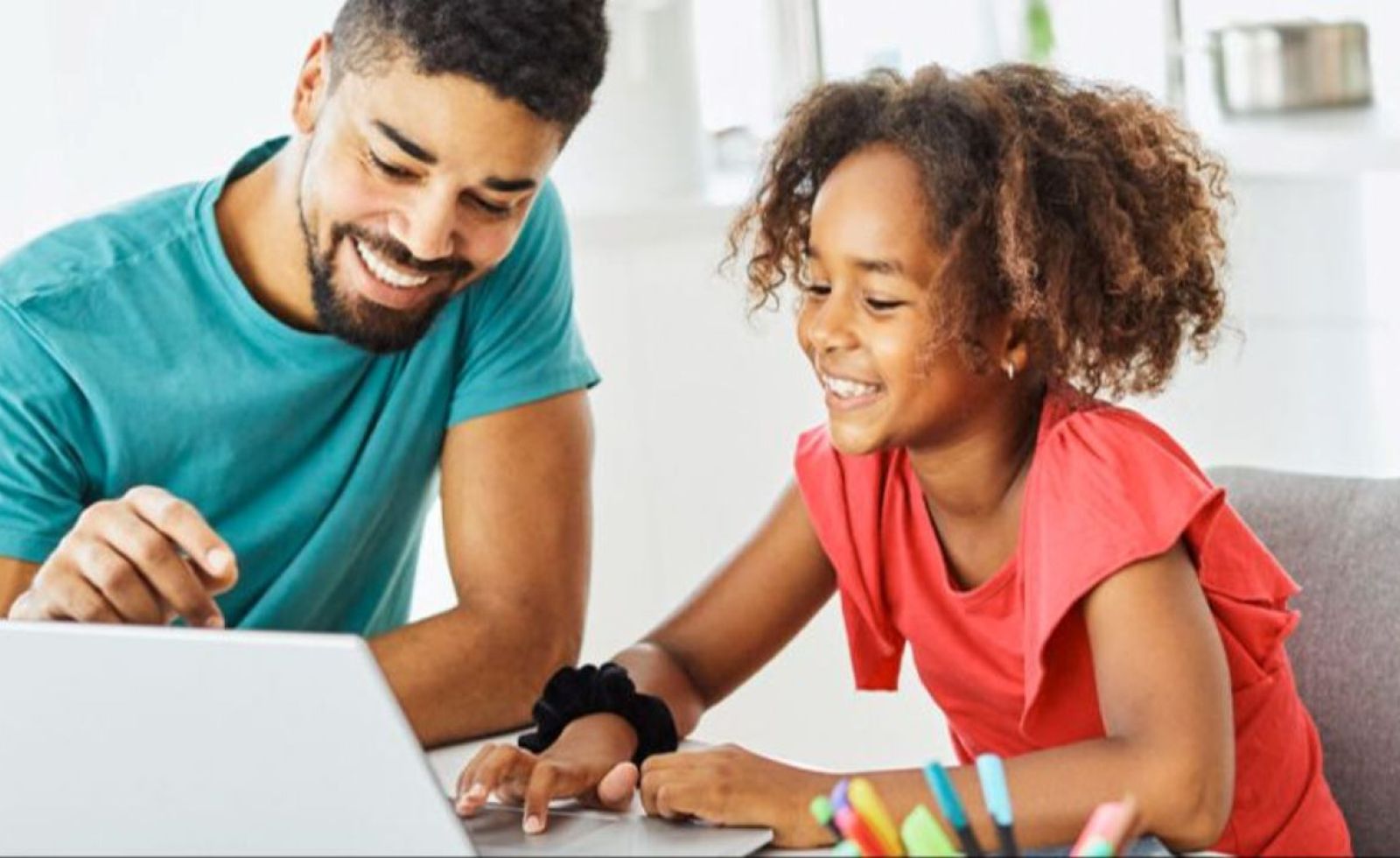 Smiling Dad helps happy daughter with her laptop.